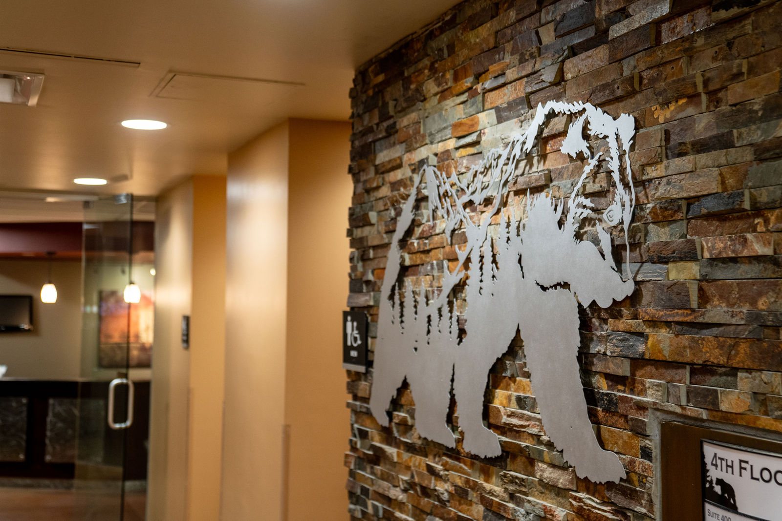 Metal bear artwork mounted on a stacked stone wall